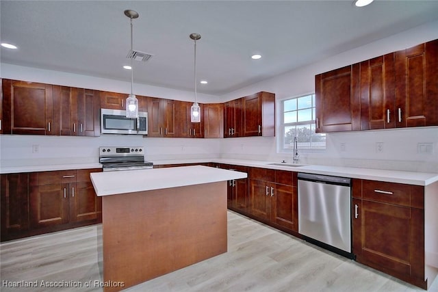 kitchen featuring pendant lighting, sink, light hardwood / wood-style flooring, a kitchen island, and stainless steel appliances