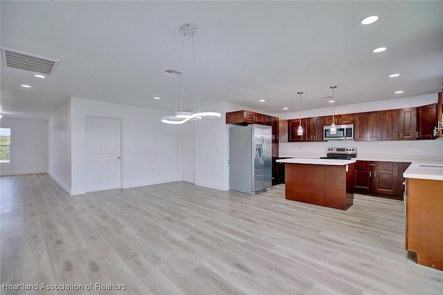 kitchen with sink, light hardwood / wood-style flooring, pendant lighting, a kitchen island, and appliances with stainless steel finishes