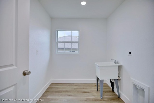 laundry area with electric dryer hookup and light hardwood / wood-style floors