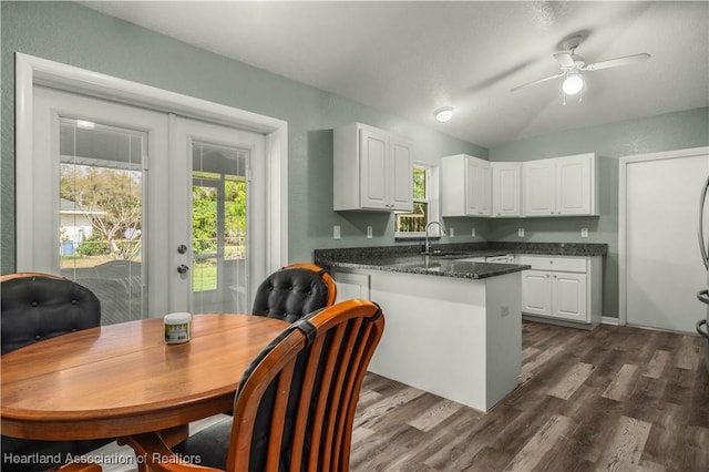 kitchen featuring kitchen peninsula, dark hardwood / wood-style flooring, white cabinets, and vaulted ceiling