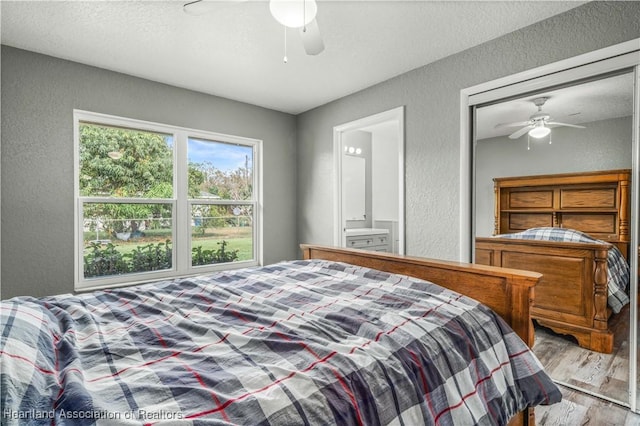 bedroom with ensuite bath, ceiling fan, light hardwood / wood-style floors, and a textured ceiling