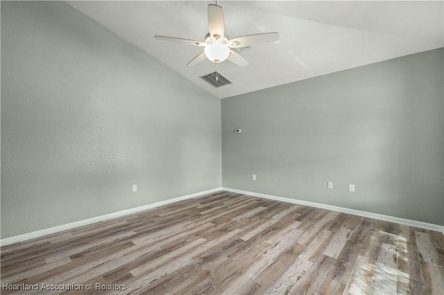 empty room with hardwood / wood-style flooring, vaulted ceiling, and ceiling fan