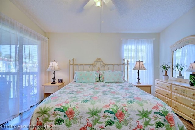 bedroom with wood finished floors, a textured ceiling, ceiling fan, and vaulted ceiling