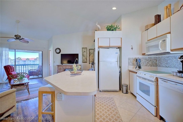 kitchen with tasteful backsplash, open floor plan, light countertops, white cabinets, and white appliances