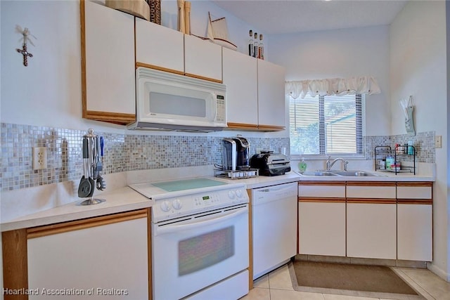 kitchen with backsplash, light countertops, light tile patterned flooring, white appliances, and a sink