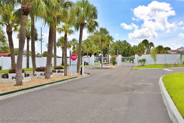 view of street with traffic signs, a gate, curbs, and a gated entry