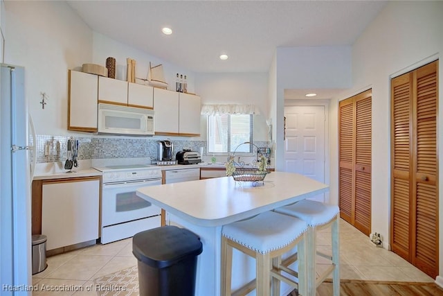 kitchen with light tile patterned flooring, white appliances, tasteful backsplash, and light countertops