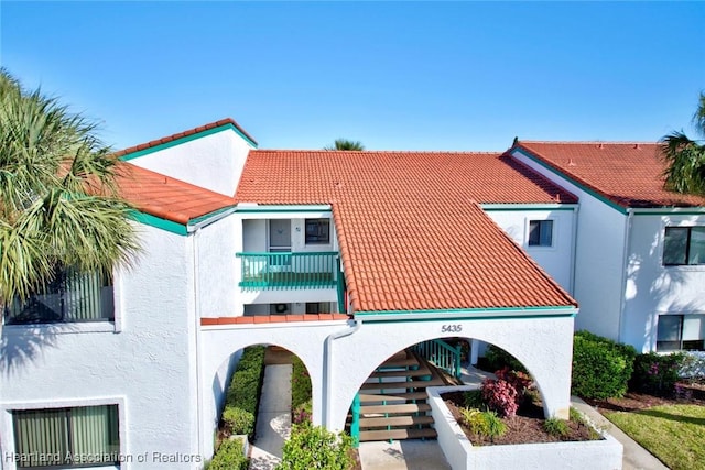 view of front of home with a balcony, a tiled roof, and stucco siding