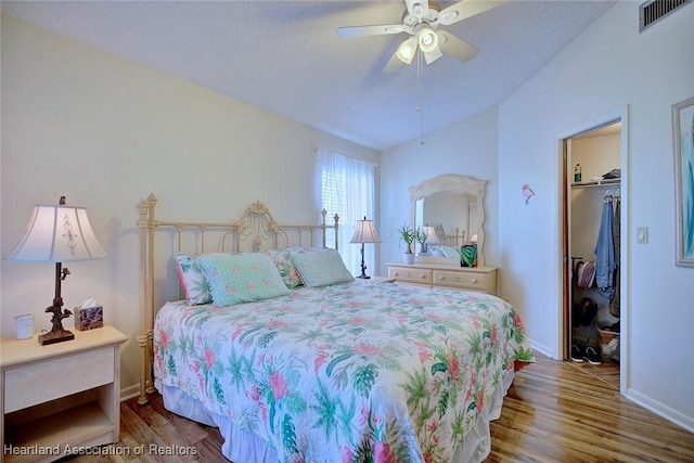 bedroom with visible vents, wood finished floors, baseboards, lofted ceiling, and ceiling fan