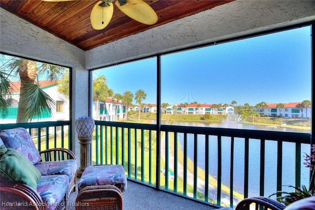 sunroom / solarium with a ceiling fan, vaulted ceiling, a water view, wooden ceiling, and a residential view