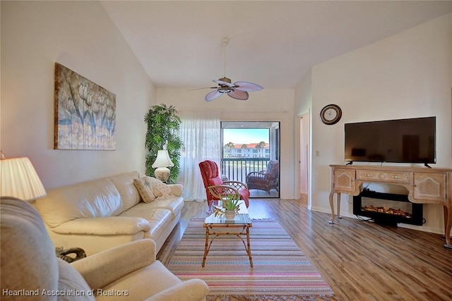 living area featuring vaulted ceiling, baseboards, ceiling fan, and wood finished floors