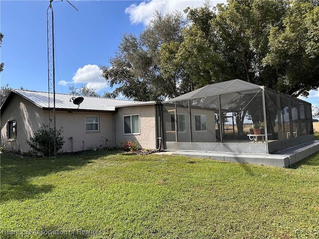 rear view of property featuring a lanai and a yard