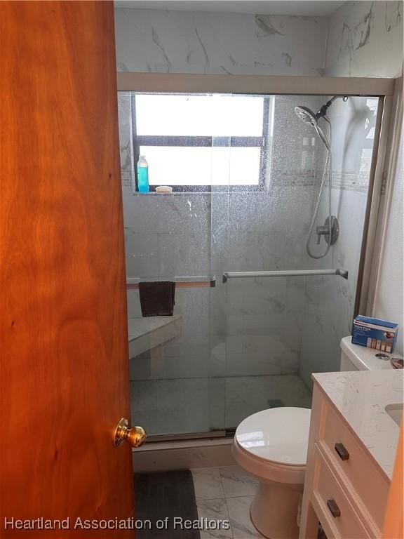 bathroom featuring tile patterned floors, vanity, an enclosed shower, and toilet