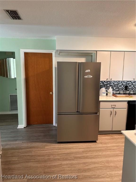 kitchen featuring white cabinetry, decorative backsplash, stainless steel fridge, and light hardwood / wood-style floors