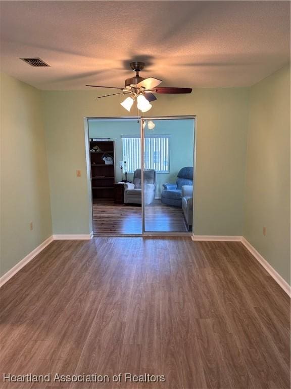 unfurnished room featuring ceiling fan, dark wood-type flooring, and a textured ceiling