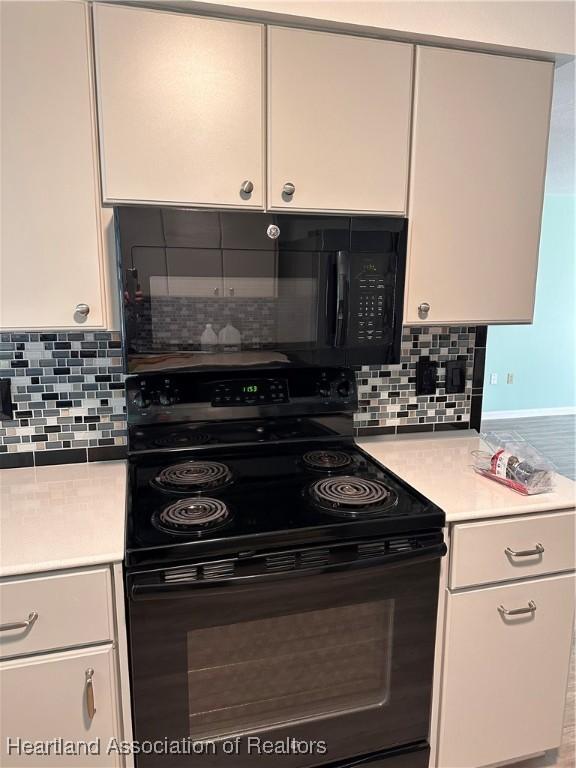 kitchen featuring white cabinets, decorative backsplash, and black range with electric cooktop