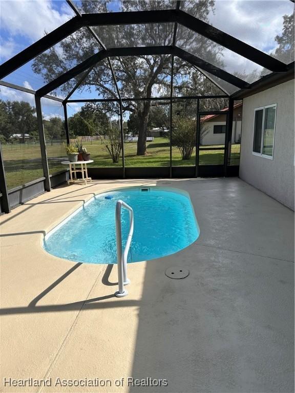 view of swimming pool featuring glass enclosure and a patio