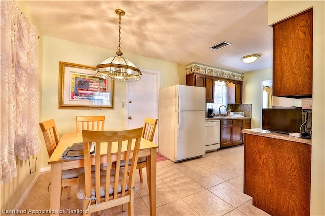 kitchen with sink, a chandelier, decorative light fixtures, white appliances, and light tile patterned floors