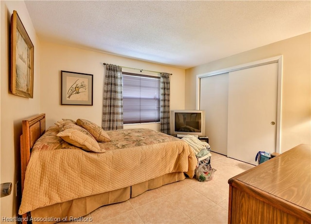 tiled bedroom with a closet and a textured ceiling