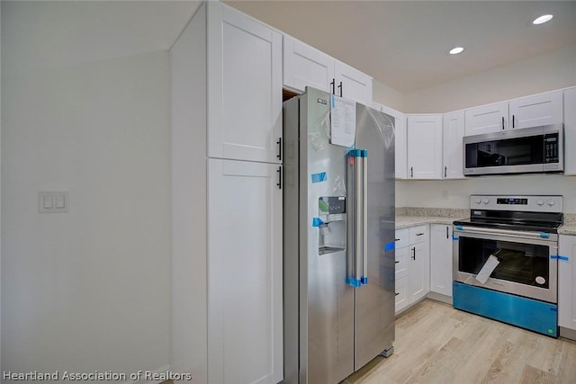 kitchen featuring white cabinets, stainless steel appliances, and light wood-type flooring