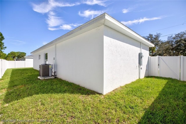 view of side of home featuring central air condition unit and a yard