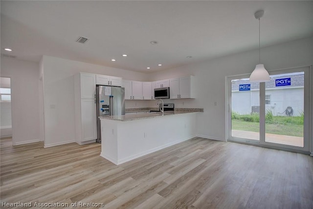 kitchen featuring sink, kitchen peninsula, decorative light fixtures, white cabinetry, and stainless steel appliances