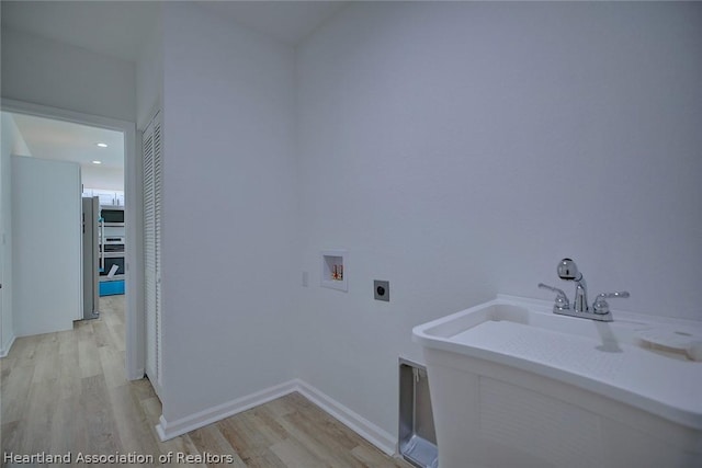 laundry area with electric dryer hookup, hookup for a washing machine, light hardwood / wood-style floors, and sink