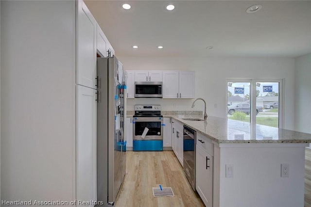 kitchen featuring sink, light hardwood / wood-style floors, light stone counters, white cabinetry, and stainless steel appliances