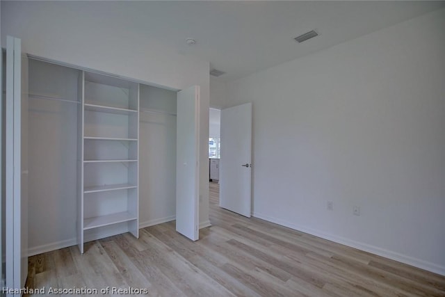 unfurnished bedroom with a closet and light hardwood / wood-style floors