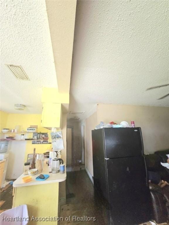 kitchen featuring kitchen peninsula, black refrigerator, and a textured ceiling