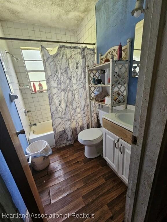 full bathroom featuring vanity, a textured ceiling, shower / bath combo with shower curtain, hardwood / wood-style floors, and toilet