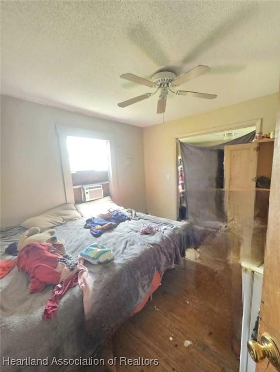 bedroom featuring ceiling fan, dark hardwood / wood-style flooring, cooling unit, and a textured ceiling