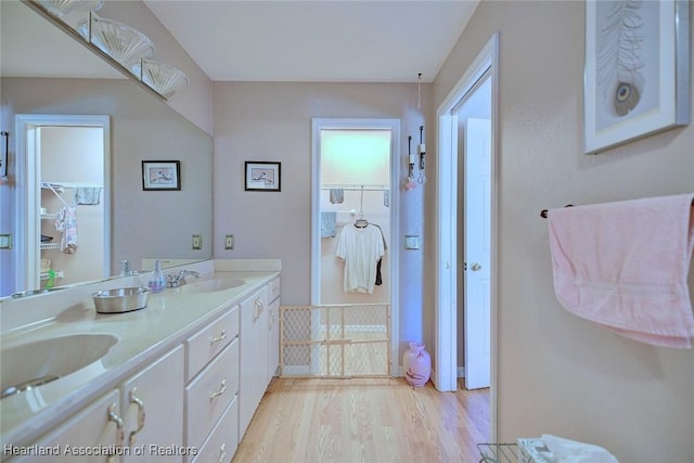 full bath with double vanity, a sink, and wood finished floors