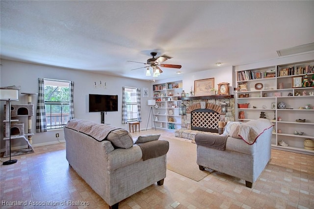 living area with built in shelves, ceiling fan, a fireplace, and baseboards