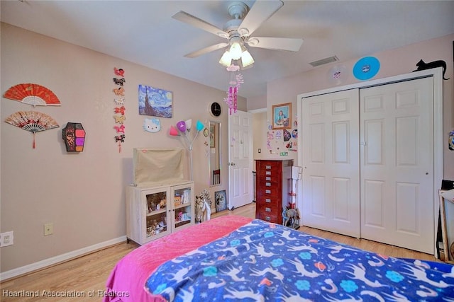 bedroom featuring light wood finished floors, baseboards, visible vents, ceiling fan, and a closet