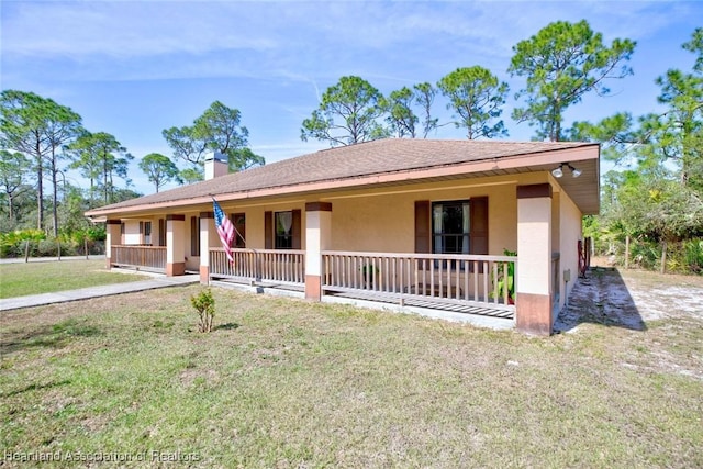 ranch-style home featuring a porch, roof with shingles, stucco siding, a front lawn, and a chimney