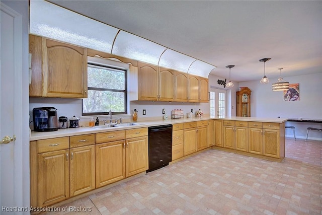 kitchen with a peninsula, black dishwasher, light countertops, and a sink