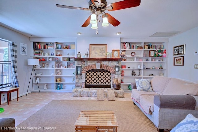 living area with built in shelves, ceiling fan, and a stone fireplace