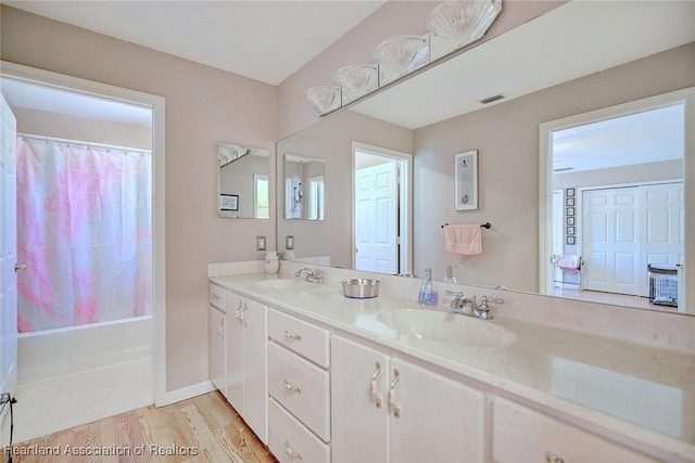 full bath featuring double vanity, baseboards, a sink, and wood finished floors