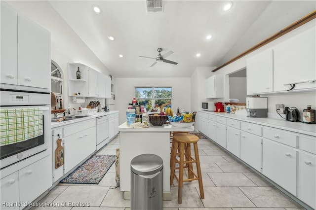 kitchen featuring white appliances, a center island, a breakfast bar area, and white cabinets