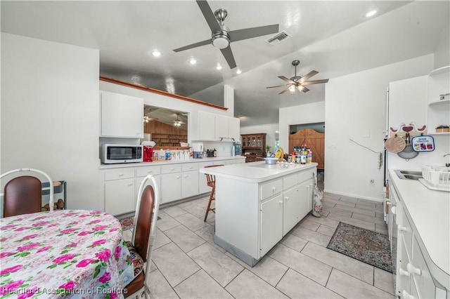 kitchen featuring a kitchen bar, sink, white cabinets, and a kitchen island