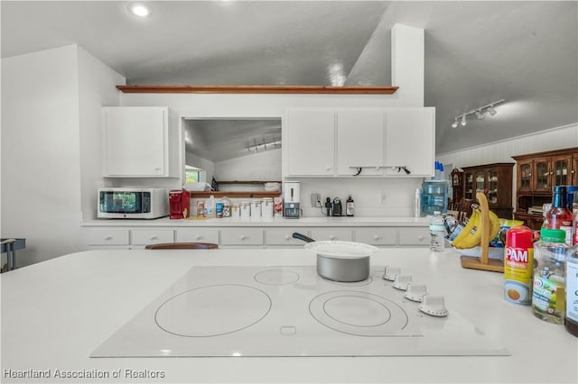 kitchen with white cabinetry, track lighting, and vaulted ceiling