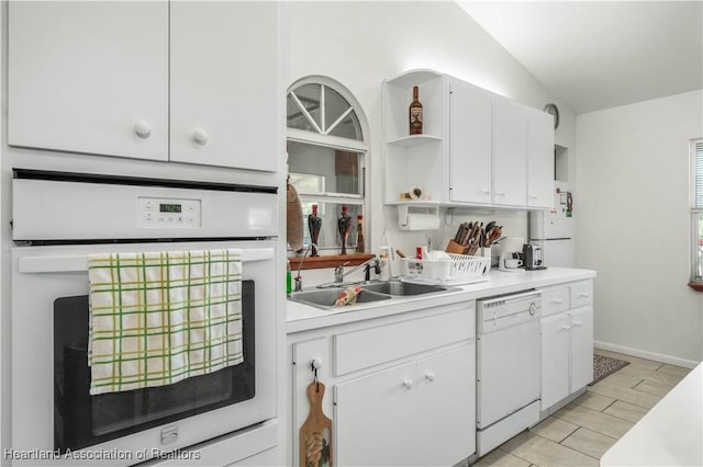 kitchen with lofted ceiling, sink, white appliances, and white cabinets