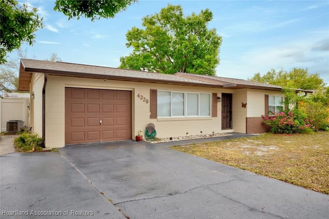 ranch-style home with central air condition unit, driveway, a front lawn, and an attached garage