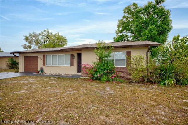 view of front of house featuring a front yard, driveway, stucco siding, a garage, and brick siding