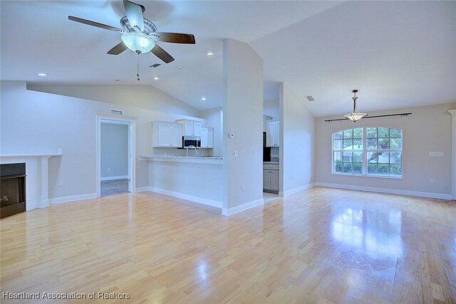 1465 Berwin Ave, Avon Park, FL 33825 - unfurnished living room featuring vaulted ceiling, ceiling fan, a fireplace, and light wood finished floors