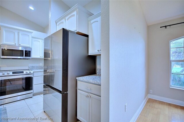1465 Berwin Ave, Avon Park, FL 33825 - kitchen featuring stainless steel appliances, lofted ceiling, white cabinetry, light stone counters, and light wood-style floors