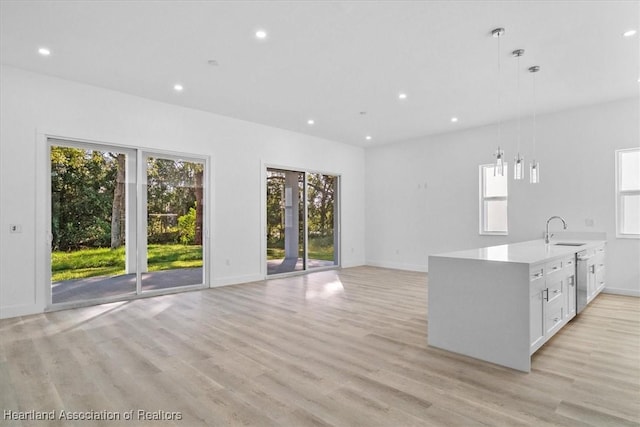 kitchen with dishwasher, hanging light fixtures, light wood-type flooring, white cabinetry, and sink