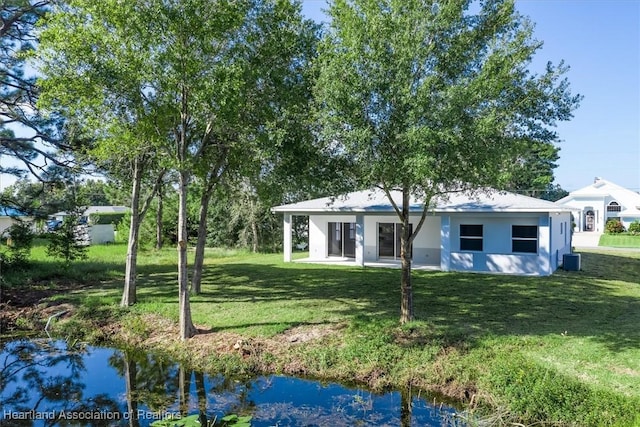 back of property with a lawn and a water view