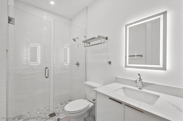 bathroom featuring toilet, vanity, and a shower with shower door